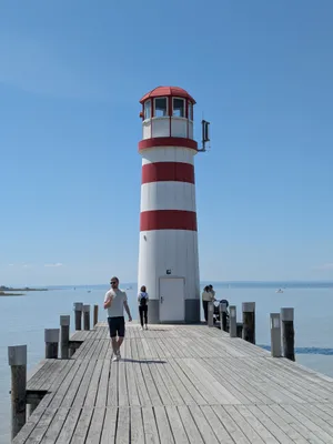 quiet lighthouse with red and white stripes on a jetty by the water